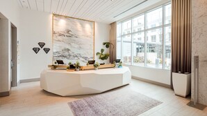 A modern reception area with a marble wall, a reception desk, and a large window with curtains. - Hyatt Centric Midtown Atlanta (Atlanta)