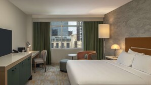 A hotel room with a bed, desk, chair, and a view of the cityscape through large windows. - Hyatt Centric Midtown Atlanta (Atlanta)