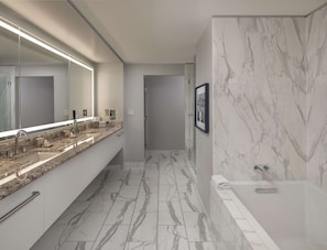 A modern bathroom with a long vanity, a large mirror, and a bathtub.