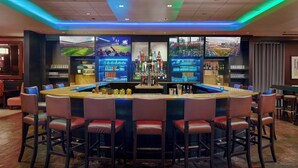 A bar area with a central bar, multiple seating options, and a large screen displaying a sports event. - Renaissance Atlanta Waverly Hotel & Convention Center (Atlanta)