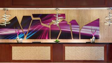 A reception desk with a modern design, featuring a large abstract painting, two decorative vases, and a unique light fixture.
