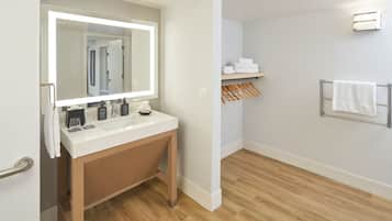 A modern bathroom with a large mirror, white sink, wooden vanity, and a towel rack.
