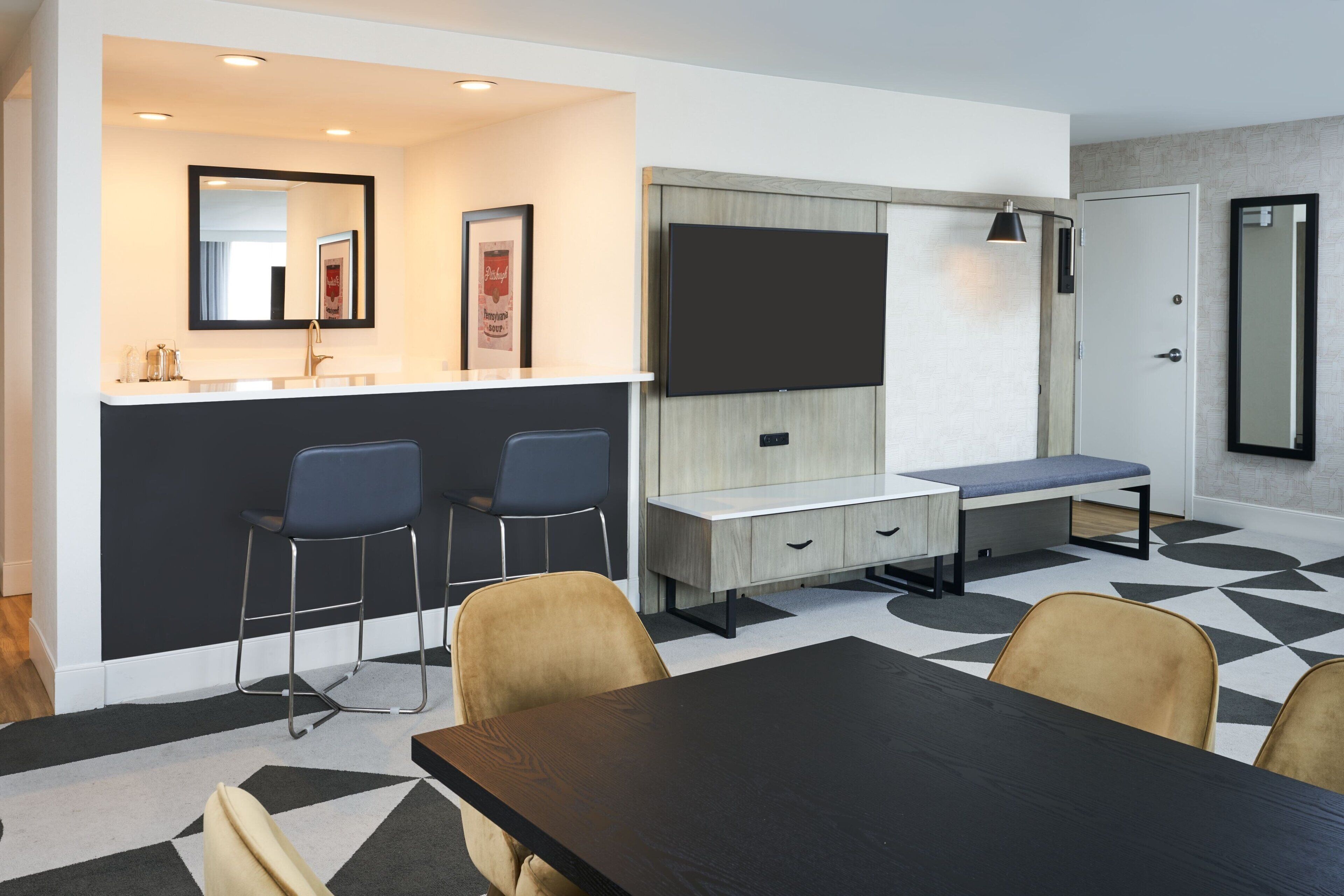A modern kitchen with a built-in stove, a dining area with a table and chairs, and a seating area with a bench.
