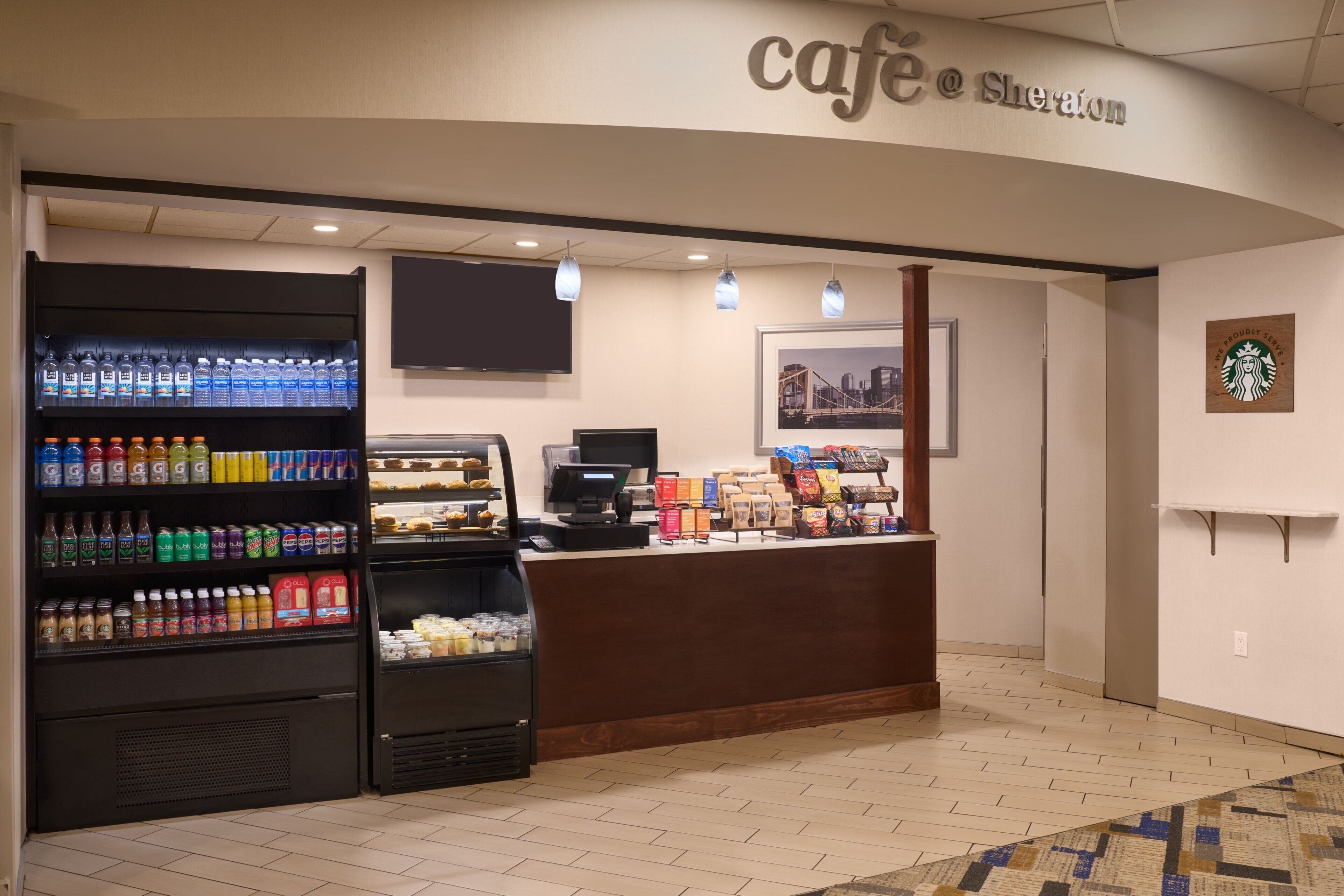 Un café doté d’un espace de libre-service pour les boissons, d’une caisse enregistreuse et du logo Starbucks sur le mur.