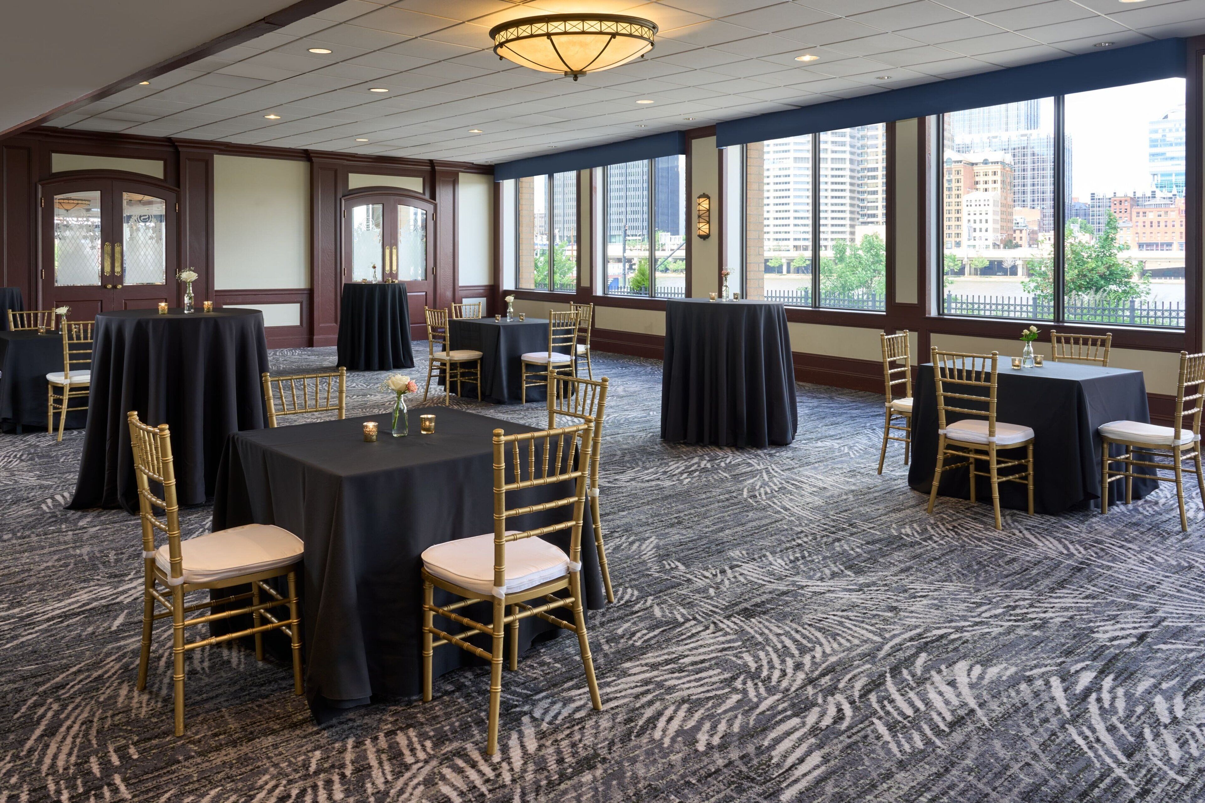 A conference room with round tables, chairs, and a carpeted floor.