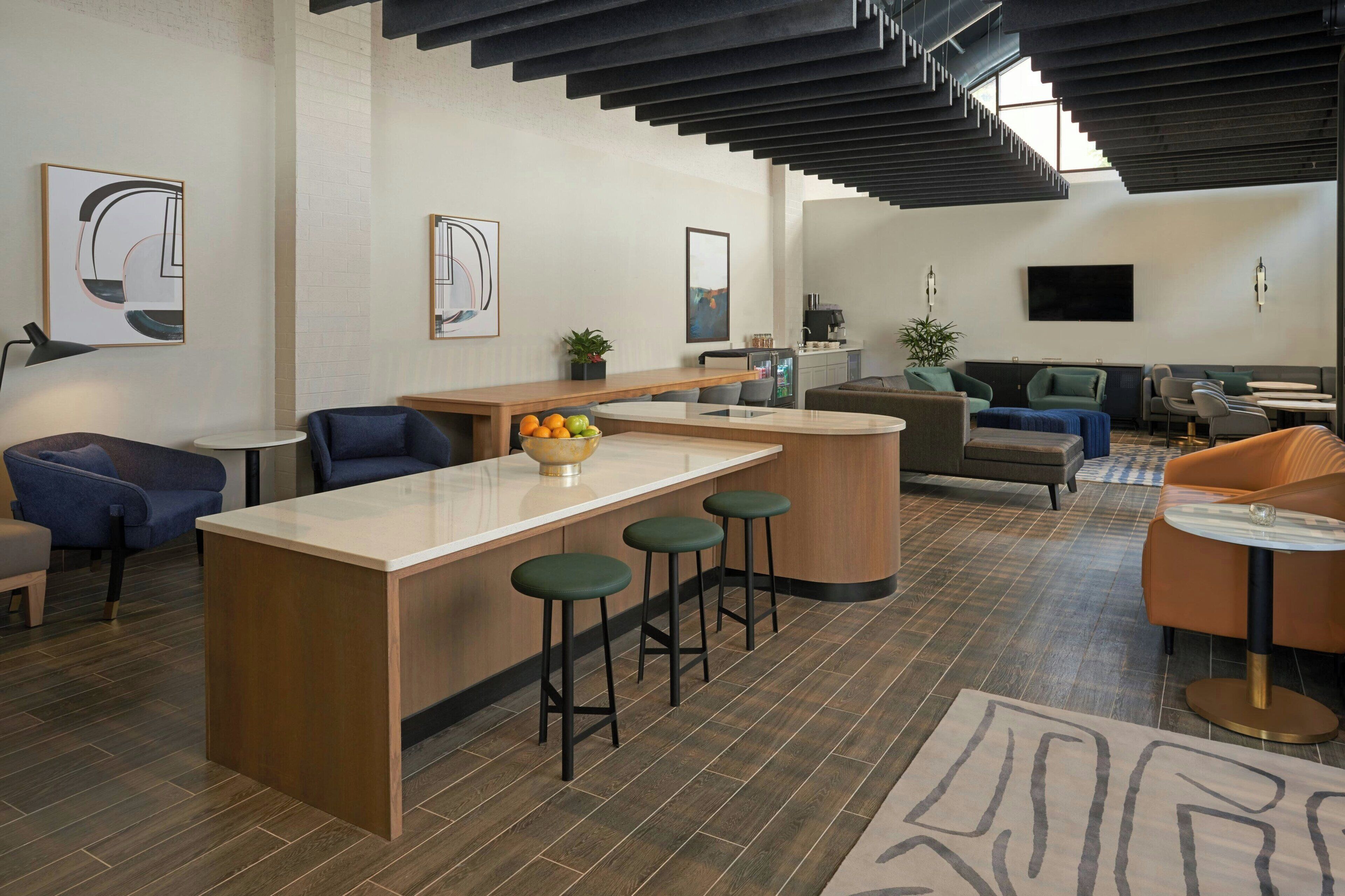 A modern kitchen with a central island, bar stools, and a seating area with a sofa and chairs.