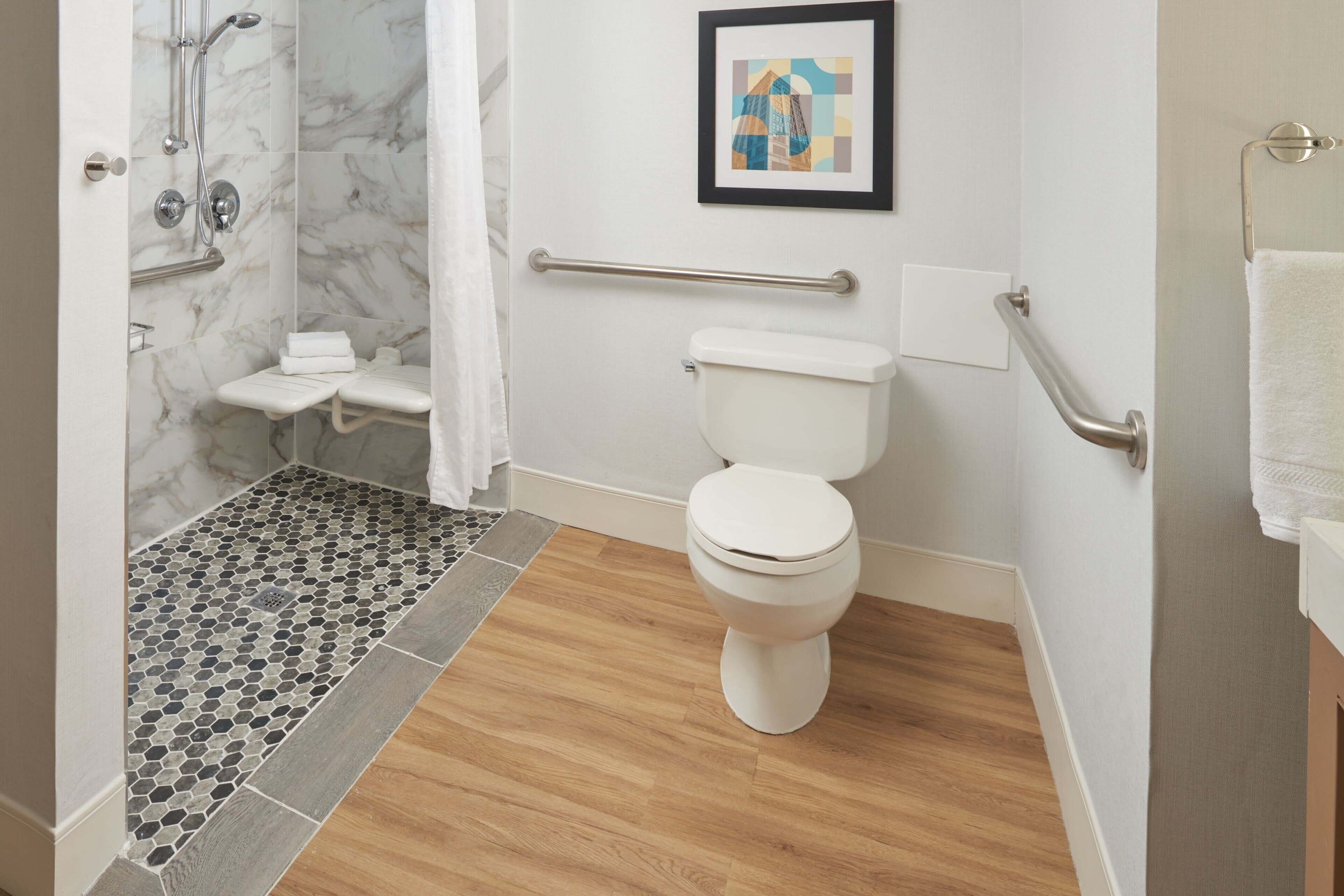Un baño moderno con ducha, inodoro y barras de apoyo.