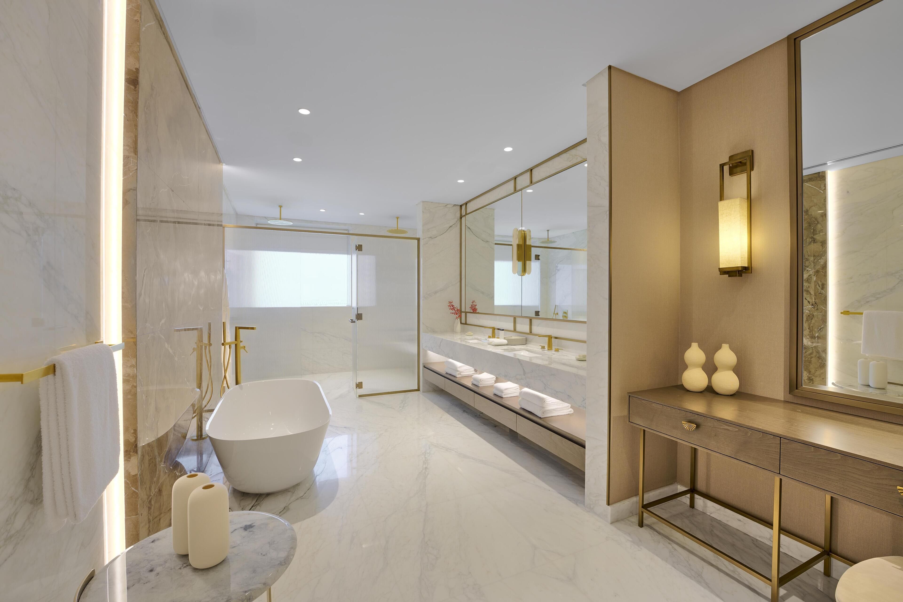 A modern bathroom with a freestanding bathtub, a vanity with a mirror, and a marble floor.