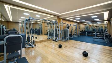 A gym with various exercise equipment, wooden flooring, and mirrored walls.