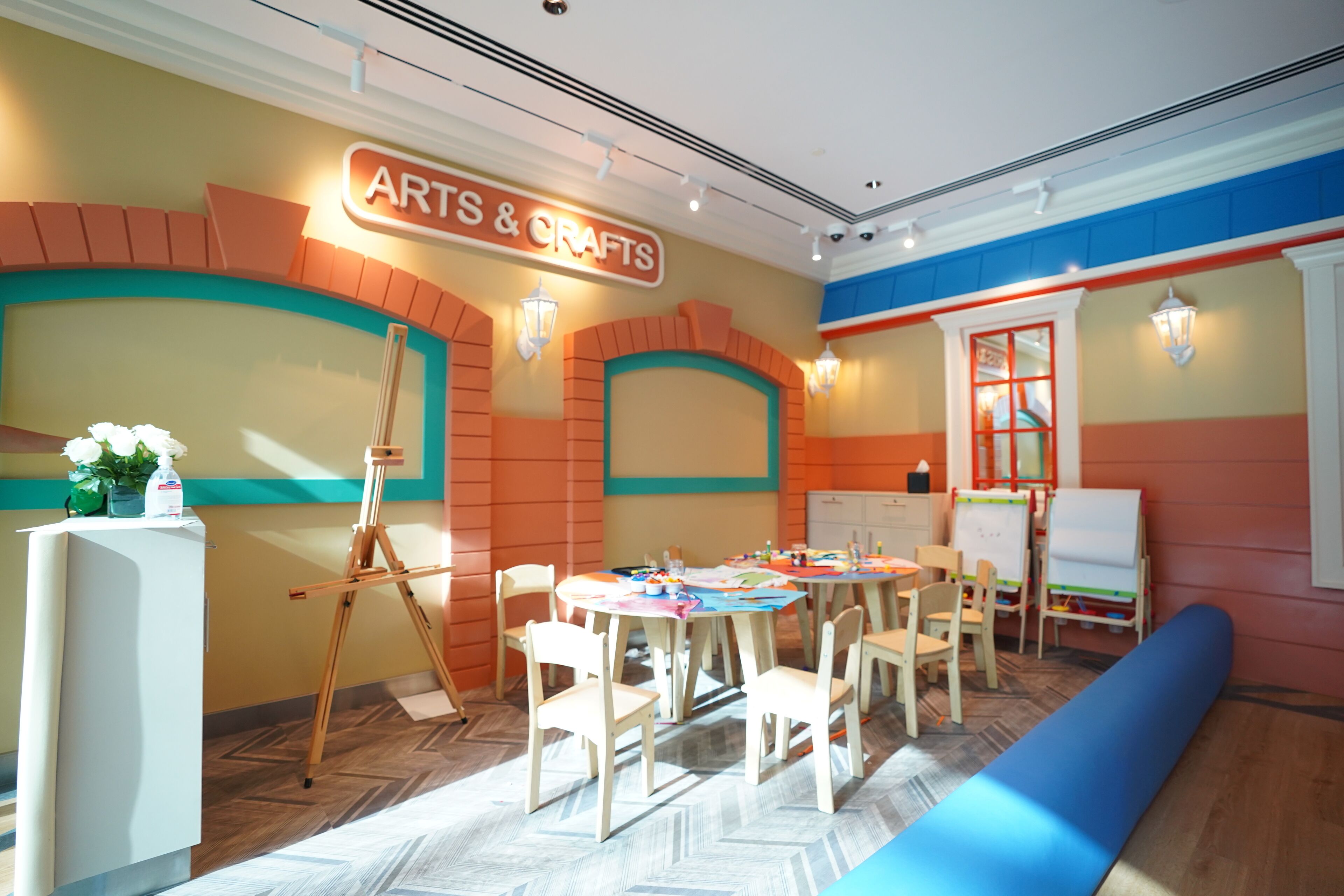 A room with a sign reading "ARTS & CRAFTS" and a whiteboard. There are several chairs and tables arranged for a meeting or class.