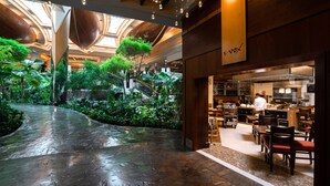 Un atriumo interior con un jardín central, una escalera y una zona de restaurante.