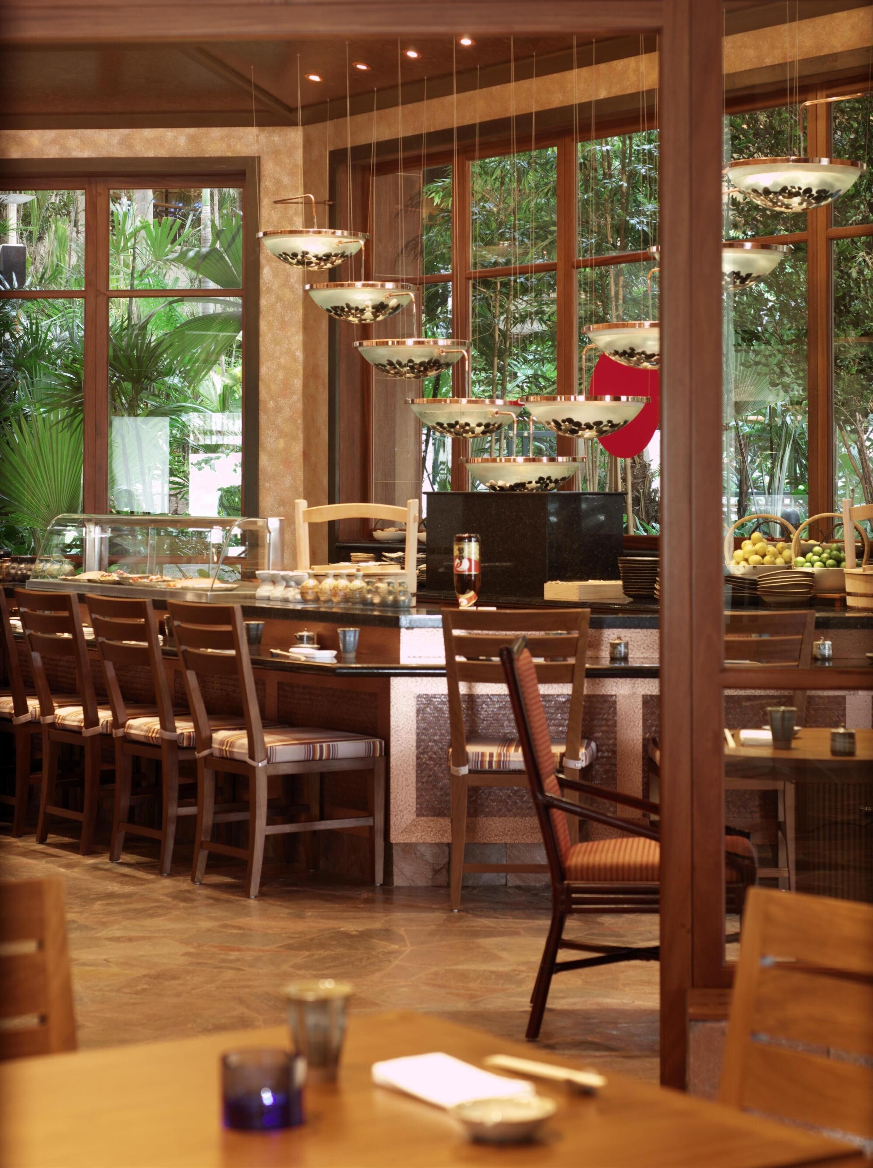 Un restaurant amb un sistema de menjar a voluntat, caires de fusta i un gran finestral que mostra vistes a la vegetació.
