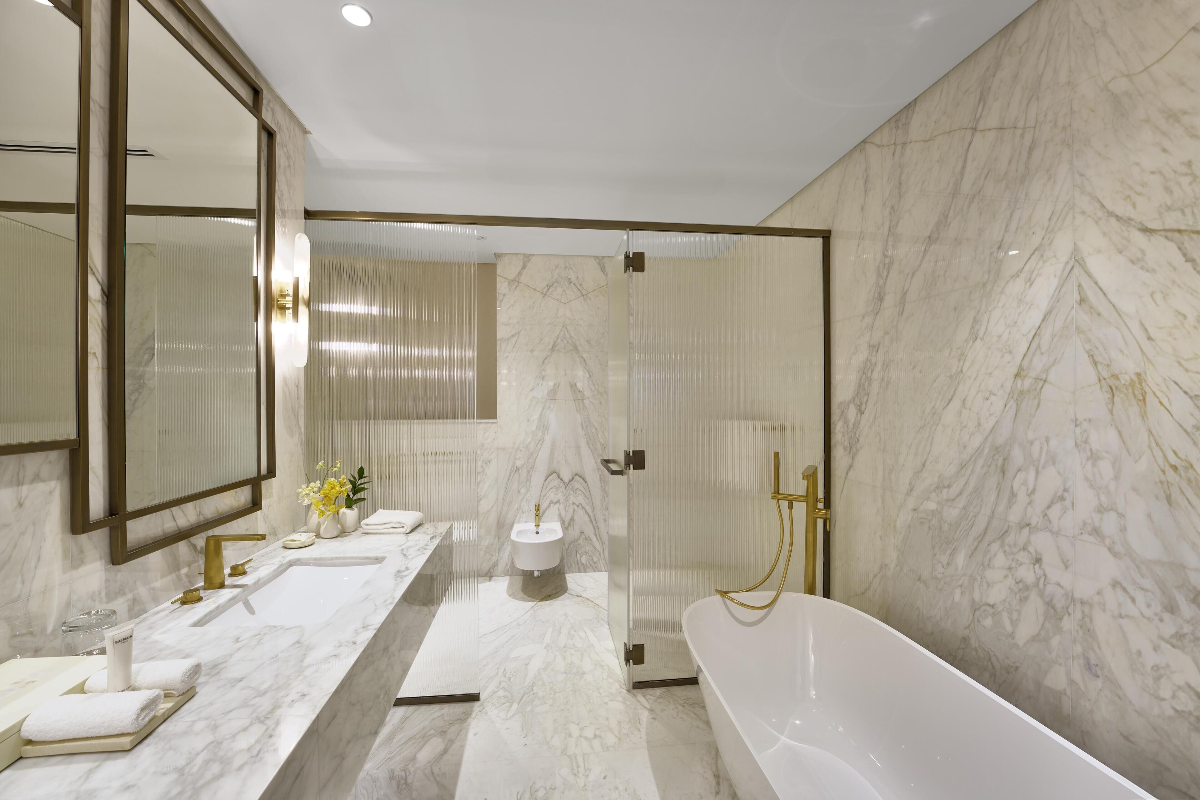 A modern bathroom with a large mirror, a bathtub, and a vanity with a sink and towel rack.
