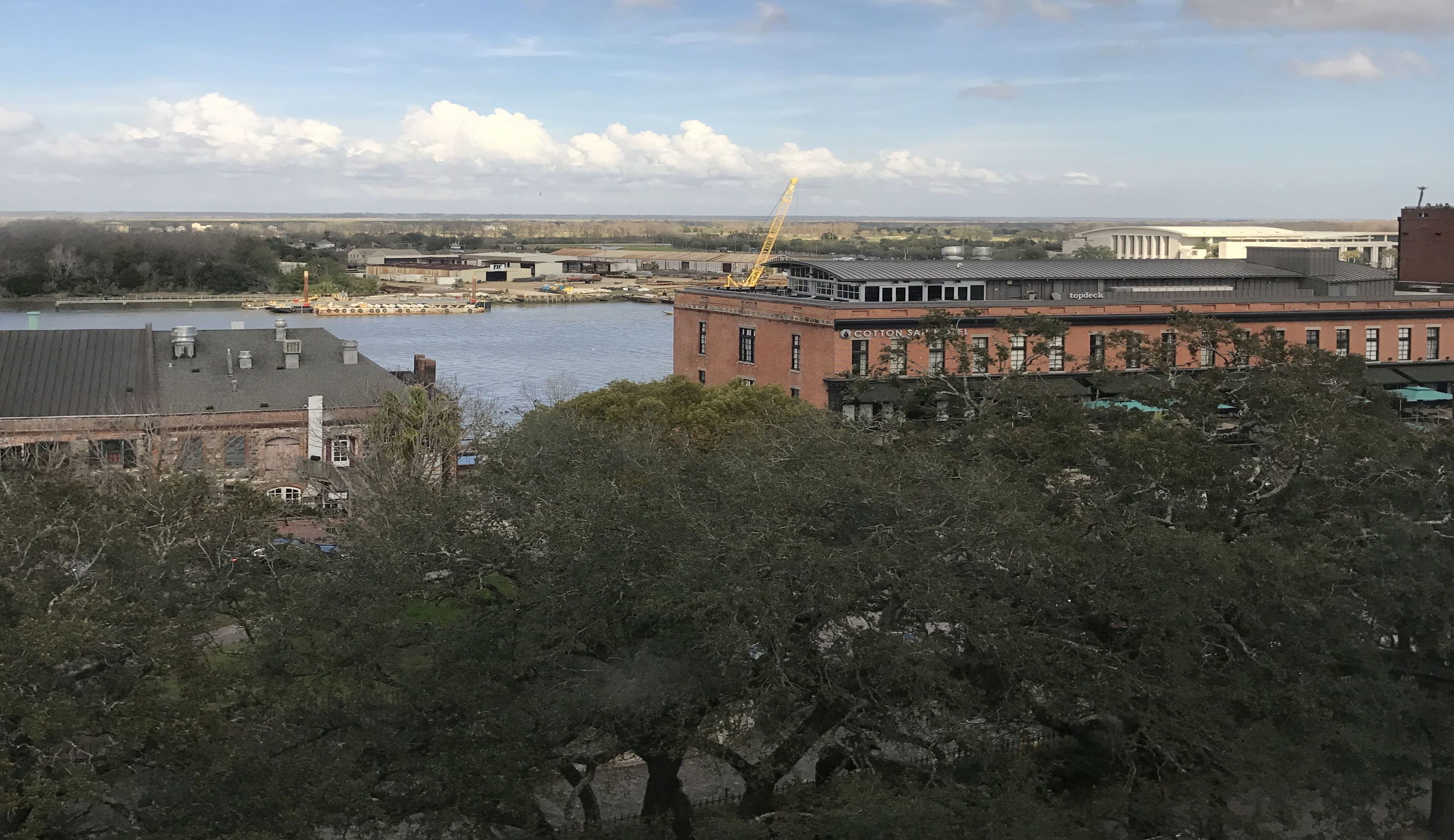 Vue sur un hôtel situé au bord de la rivière, avec un bâtiment en briques, une grue et un quai.