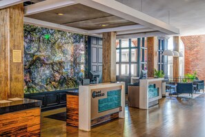 A hotel reception area with a large mural, wooden accents, and a modern reception desk.