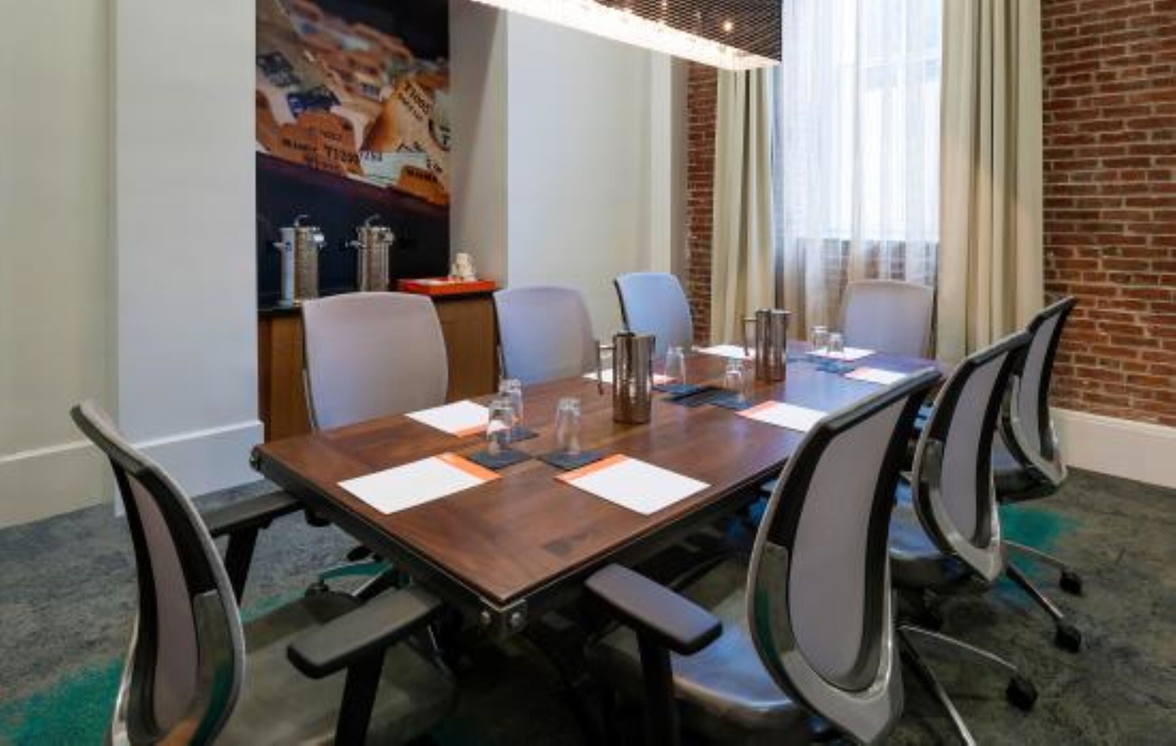 Un salón de conferencias con una larga mesa, seis sillas y una pared de ladrillo.