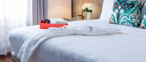 A neatly made bed with a white comforter, a red box, and a white pillow with a logo.