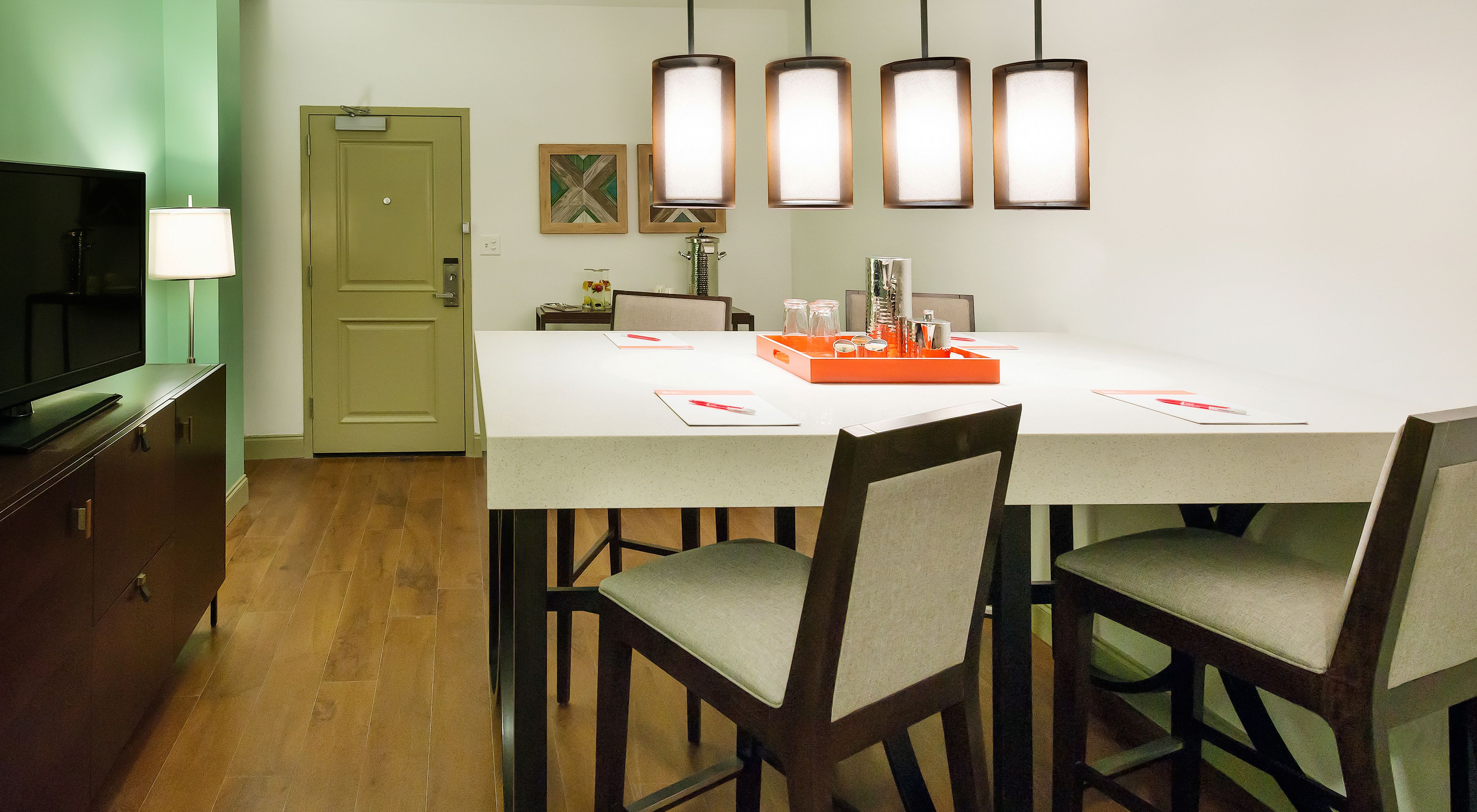 A dining area with a table, chairs, a television, and a door.
