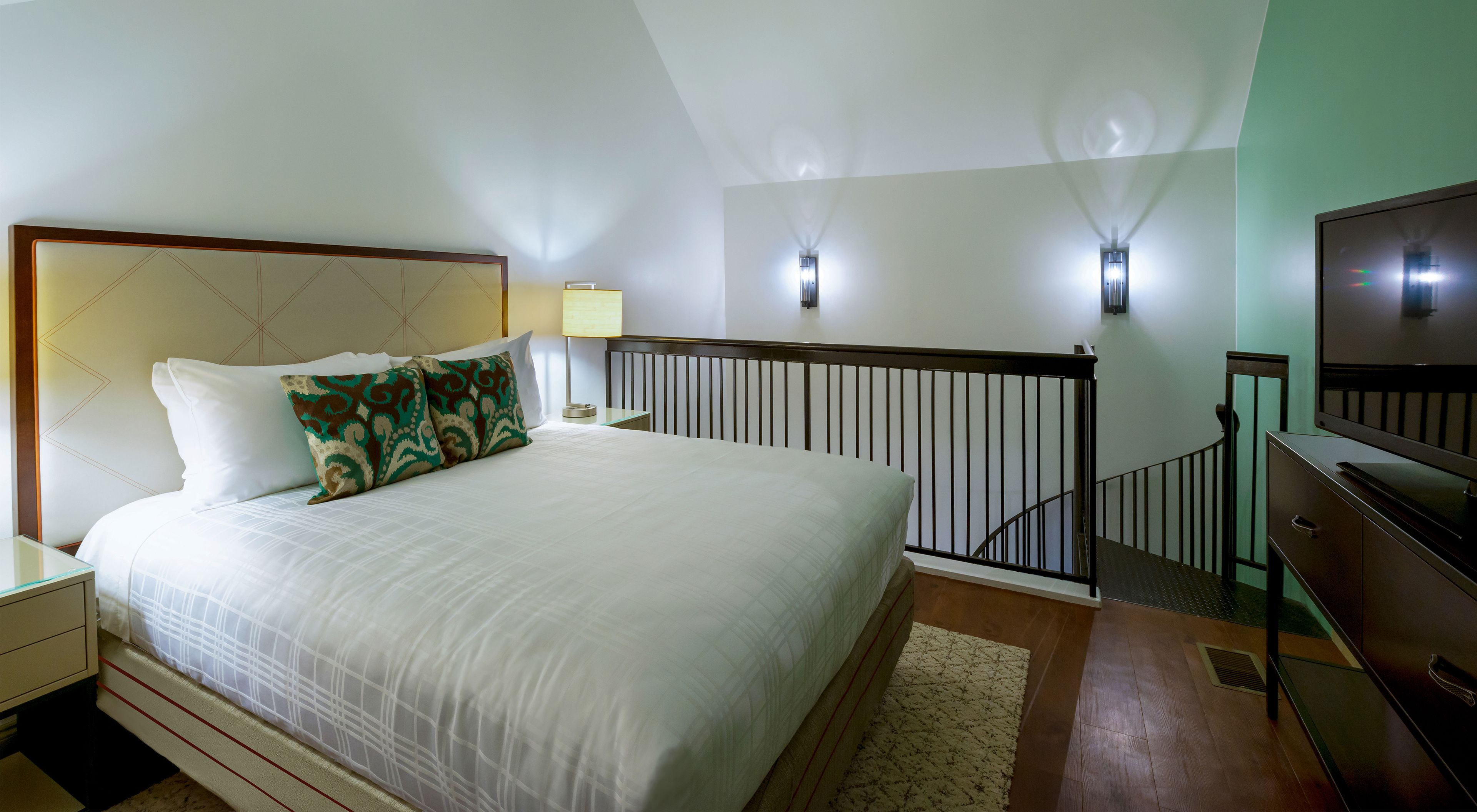 Une chambre d’hôtel avec un grand lit, une télévision, un bureau et un escalier.