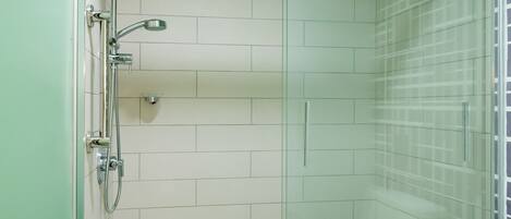 Une salle de bain moderne avec une douche à parois de verre, des murs recouverts de carreaux blancs et des toilettes blanches.