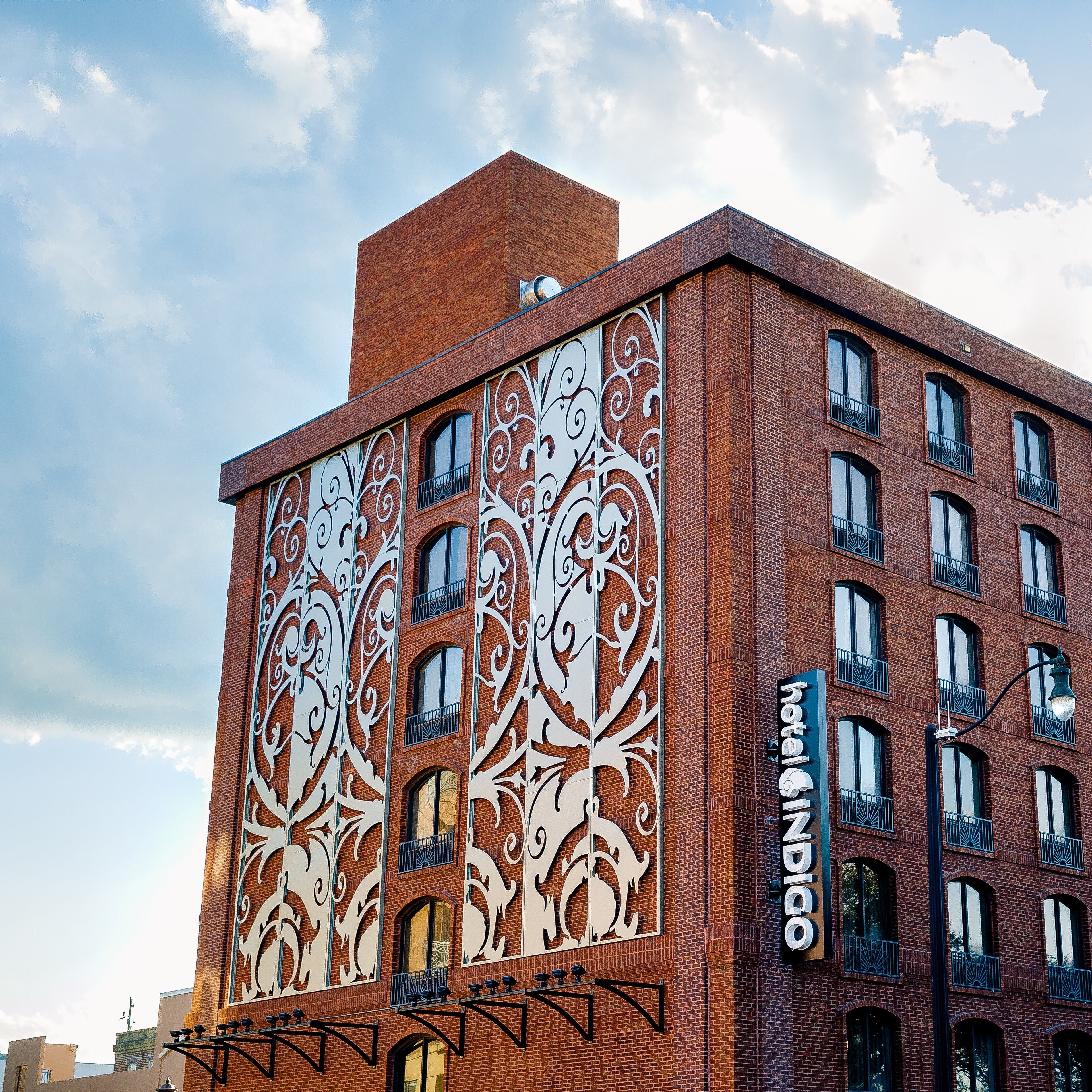 A hotel with a red brick facade, ornate white window designs, and multiple balconies.