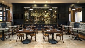 A restaurant with dark wood paneling, wooden tables and chairs, and a large mural of trees on the wall.