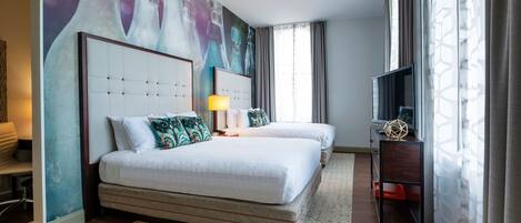 Habitación de hotel con dos camas, un cuadro grande en la pared, un televisor sobre un mueble y una ventana con cortinas.