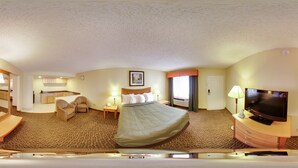 Une chambre d’hôtel comprenant un lit, un bureau, une chaise, une télévision et une salle de bain.