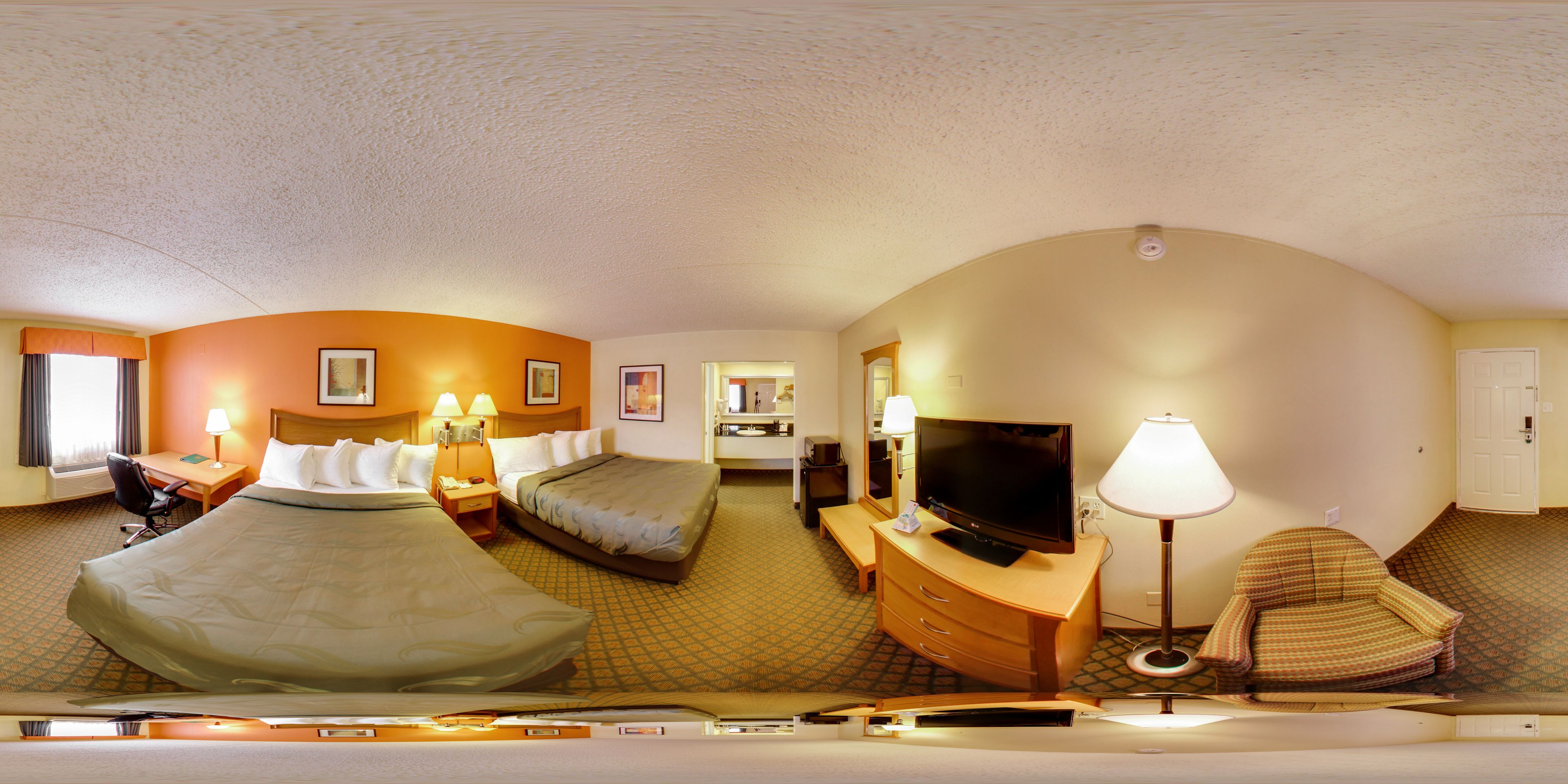 A hotel room with two beds, a TV, a desk, and a chair.