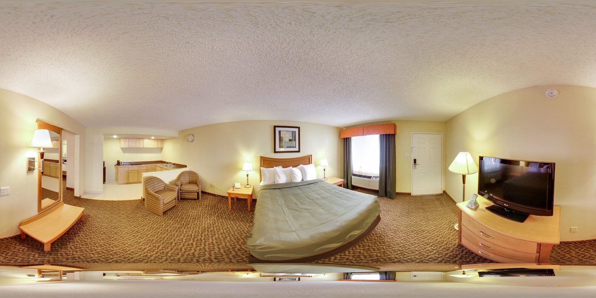 A hotel room with a bed, a TV, a desk, a chair, a small table, and a window.