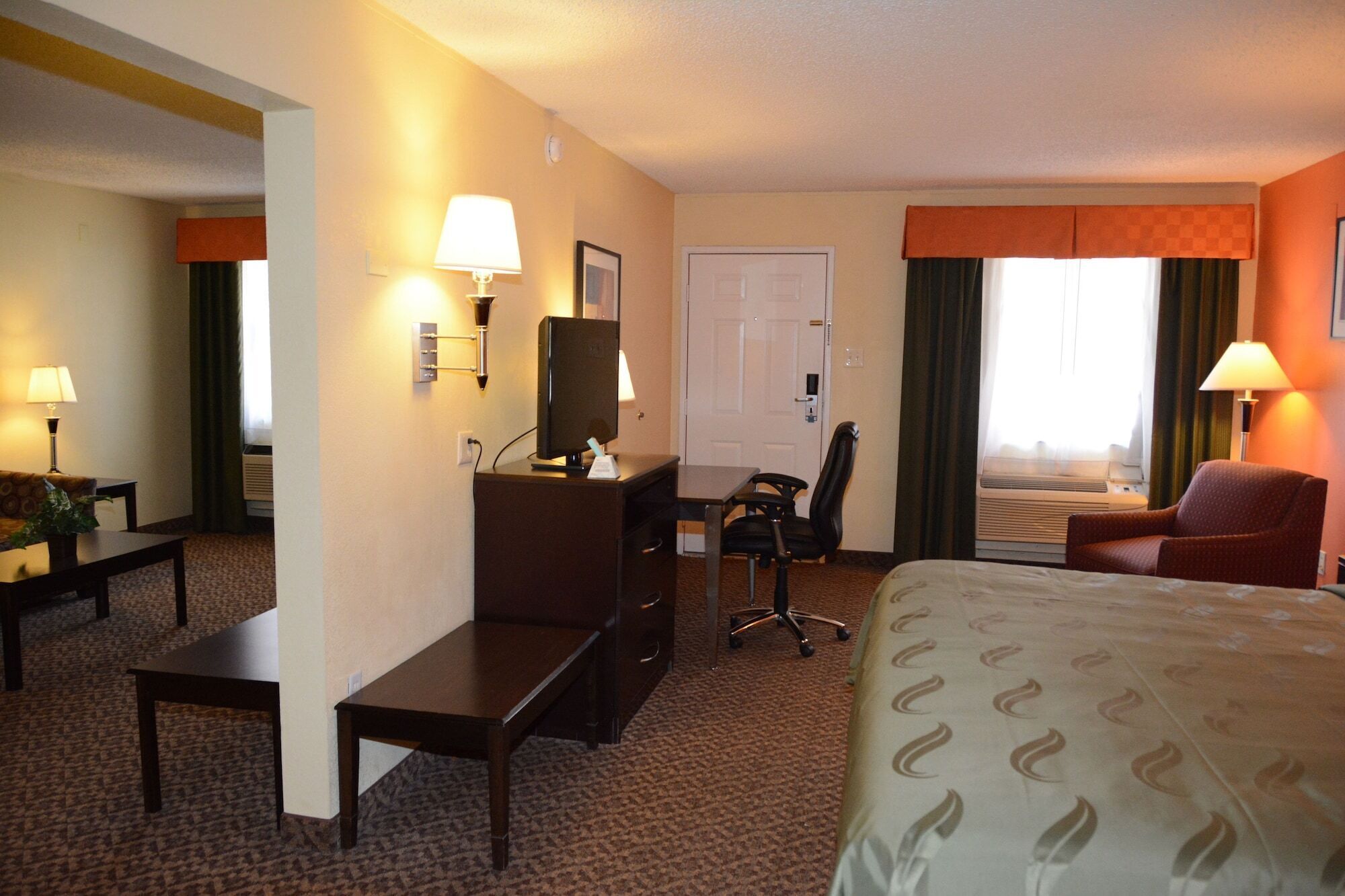 A hotel room with a bed, desk, chair, and a TV.