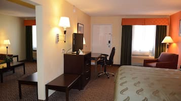 A hotel room with a bed, desk, chair, and a TV.