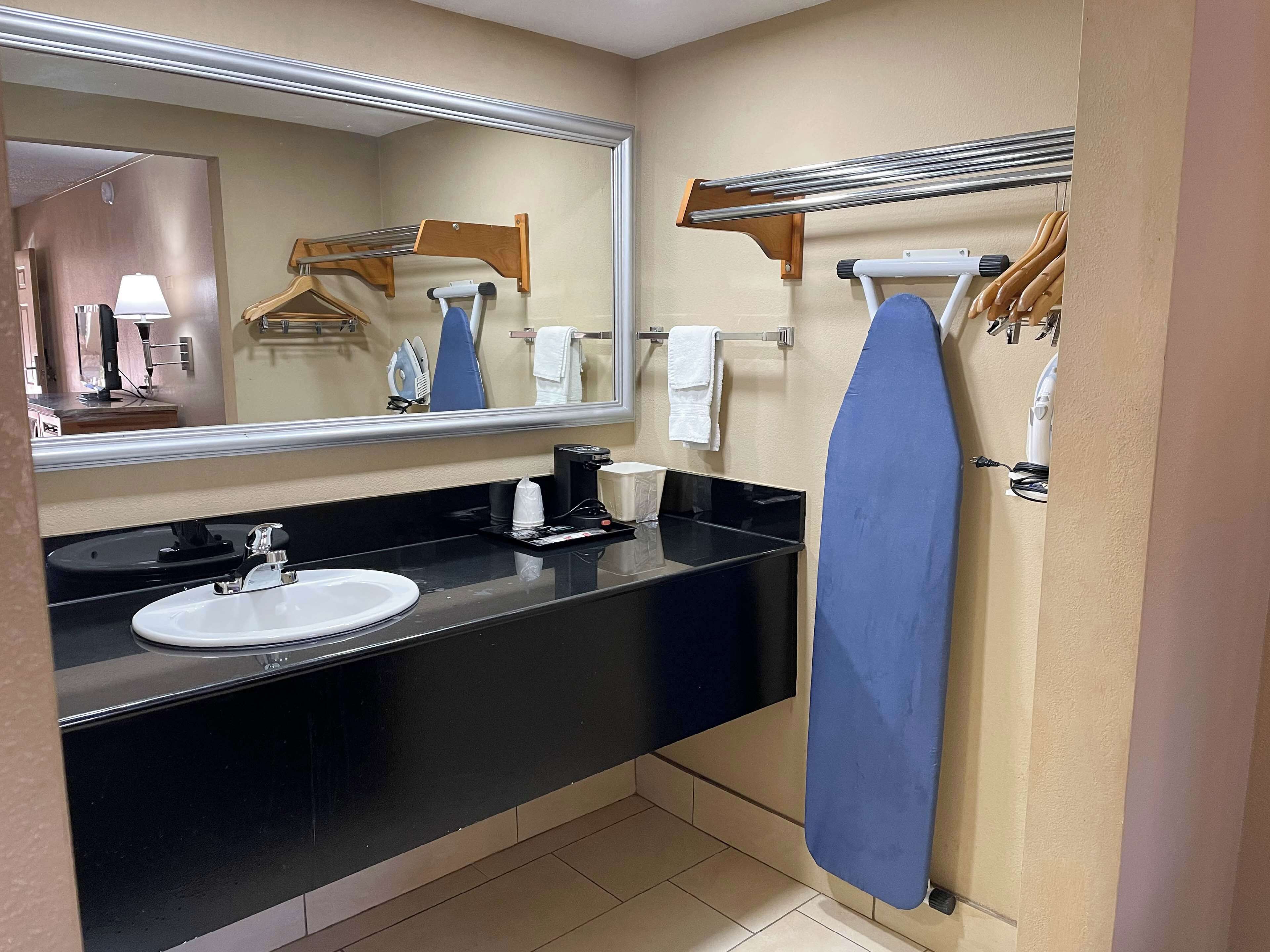 Un baño moderno con encimera negra, lavabo blanco, espejo y toallero.