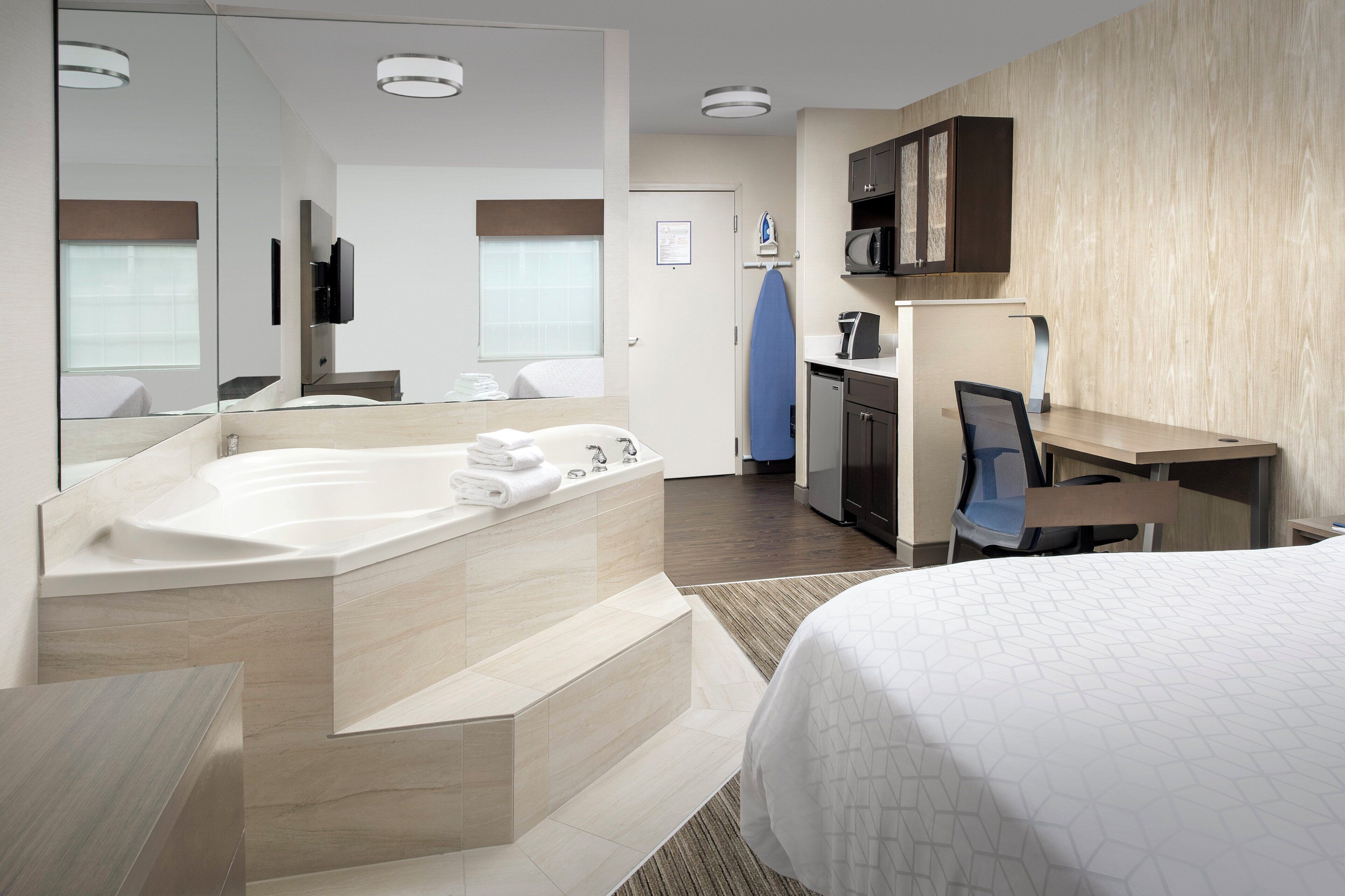 Habitació d'hotel amb una banyera gran, escriptori amb cadira, microones i petita cuina.