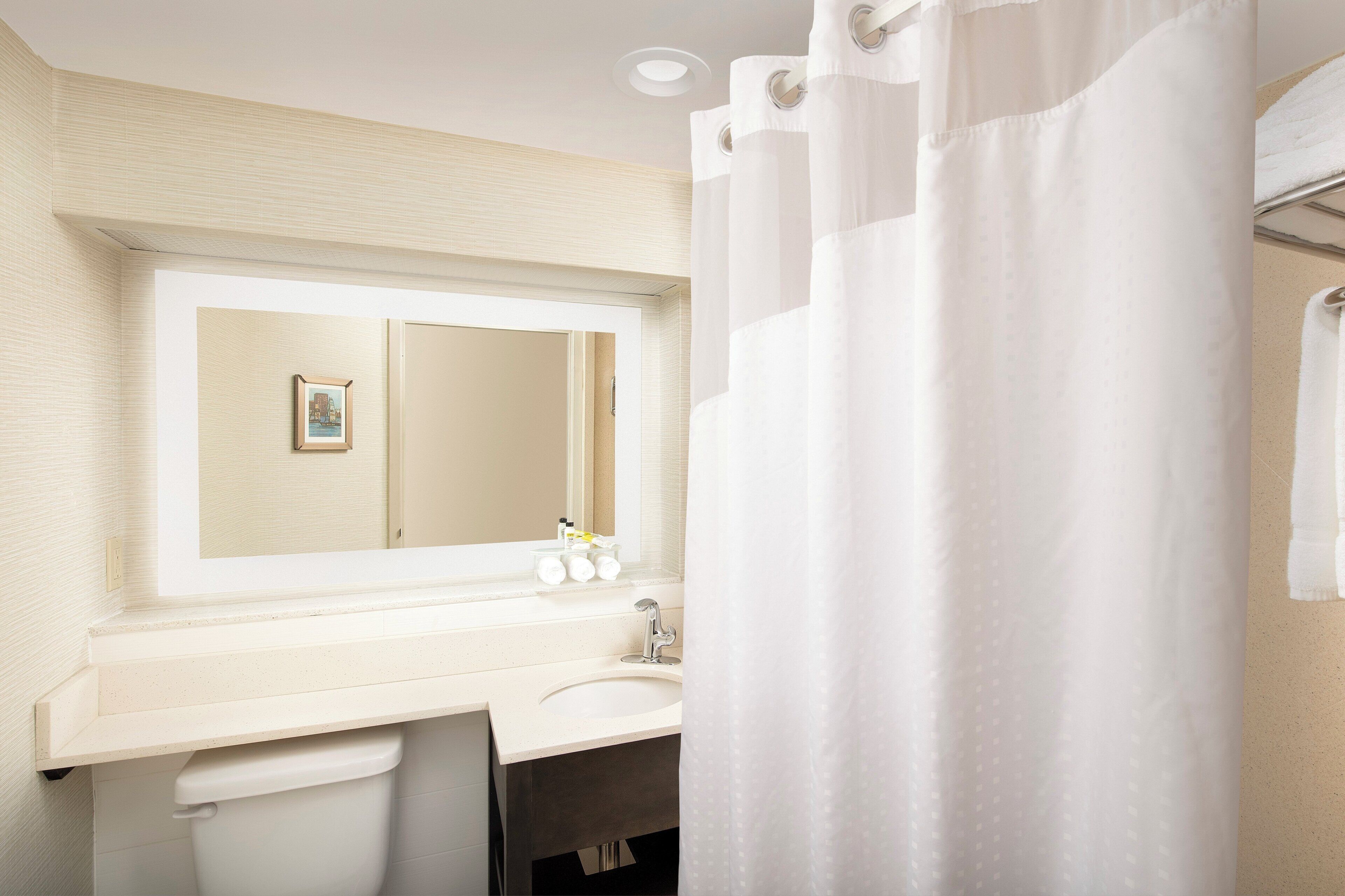 A bathroom with a white sink, mirror, and shower curtain.