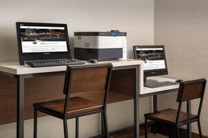 Un espacio de oficina moderno con dos monitores, un teclado y dos sillas de madera.