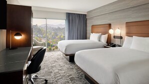A hotel room with two beds, a desk, a chair, and a large window offering a view of the mountains. - Courtyard by Marriott Los Angeles - Sherman Oaks (Sherman Oaks)