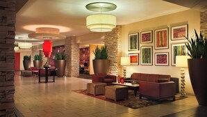 A spacious lobby with a modern design, featuring a seating area with sofas and armchairs, a coffee table, and a large potted plant. - Courtyard by Marriott Los Angeles - Sherman Oaks (Sherman Oaks)