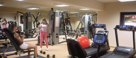 A gym with exercise equipment, including a bench, dumbbells, and treadmills.