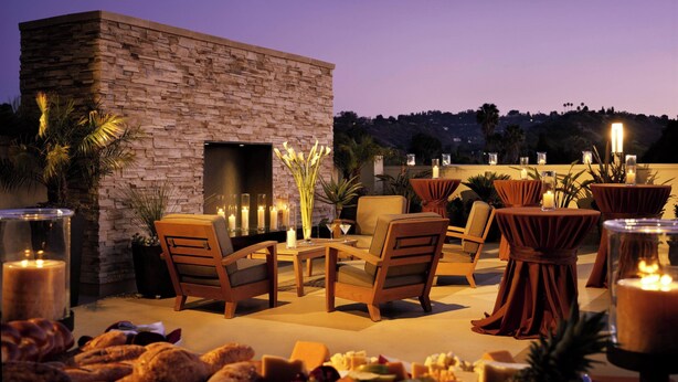An outdoor patio with stone walls, seating, candles, and a view of the hills. - Courtyard by Marriott Los Angeles - Sherman Oaks (Sherman Oaks)