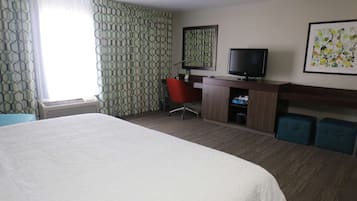 Habitación de hotel con una cama grande, un escritorio con computadora, televisor y una silla.