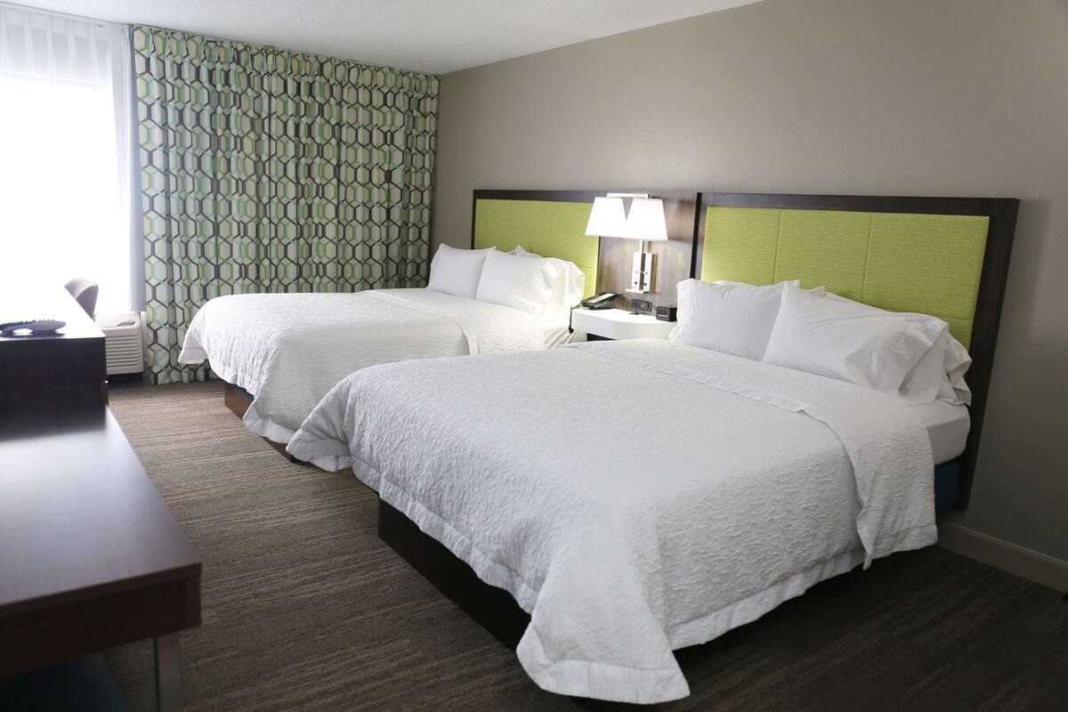 A hotel room with two beds, a desk, and a telephone.