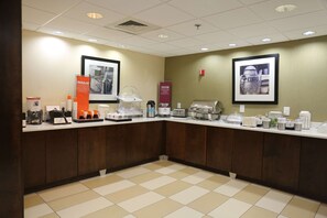 A hotel reception area with a counter, coffee machines, and a framed picture of a coffee pot.