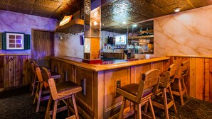 A bar area with wooden furniture and a marble wall. - Deadwood Miners Hotel (Deadwood)