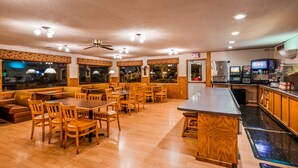 A restaurant with wooden furniture, a bar area, and a ceiling fan. - Deadwood Miners Hotel (Deadwood)