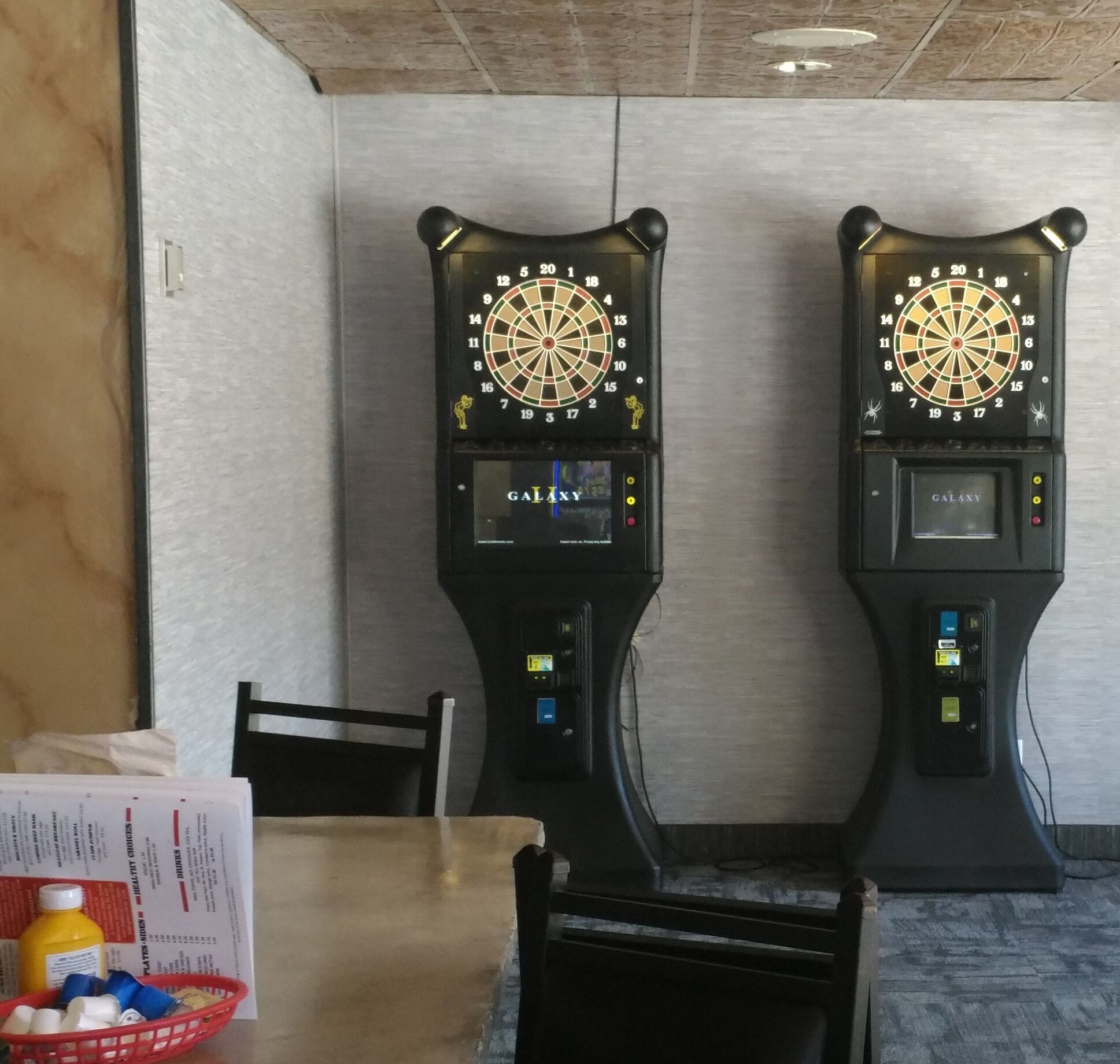 Two dartboards mounted on a wall with a digital display and control panel below each.