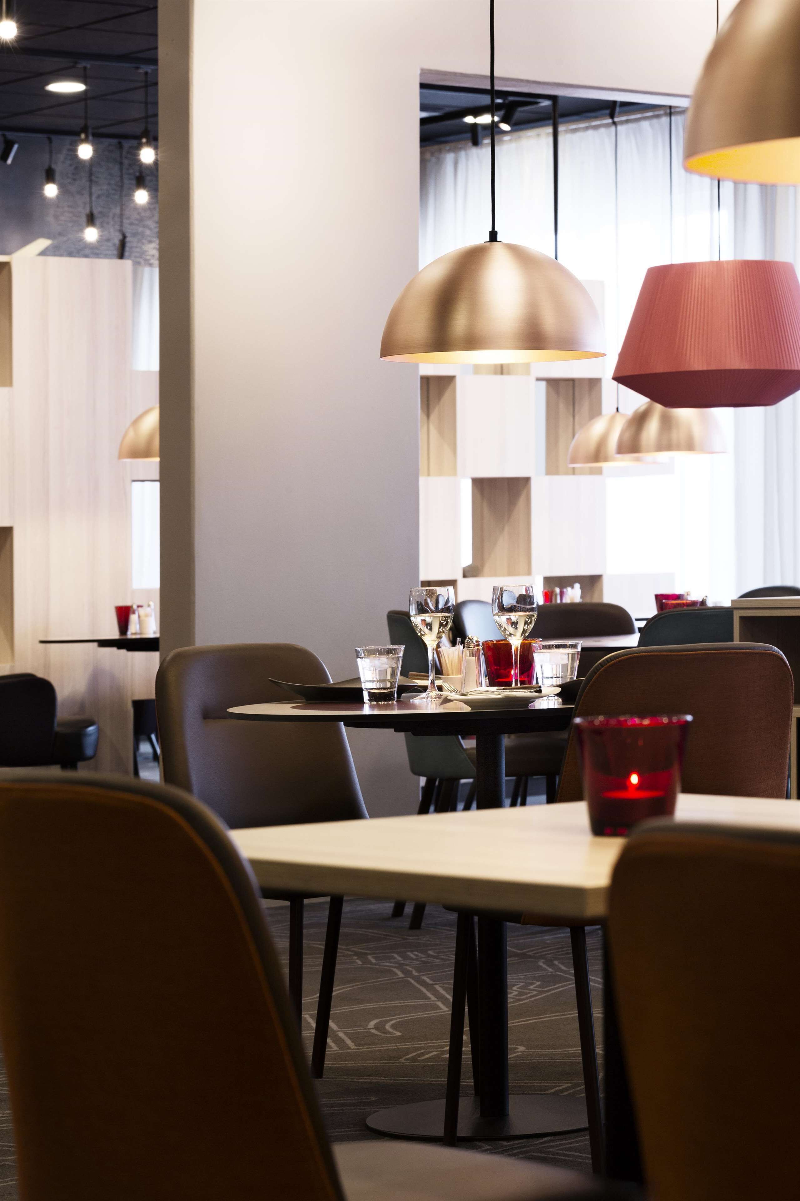 A modern dining area with pendant lighting, a table set with glasses, and a red candle.