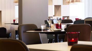 A modern dining area with pendant lighting, a table set with glasses, and a red candle.