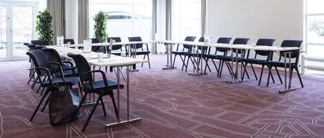 Una sala de conferencias con una larga mesa, sillas y piso alfombrado.