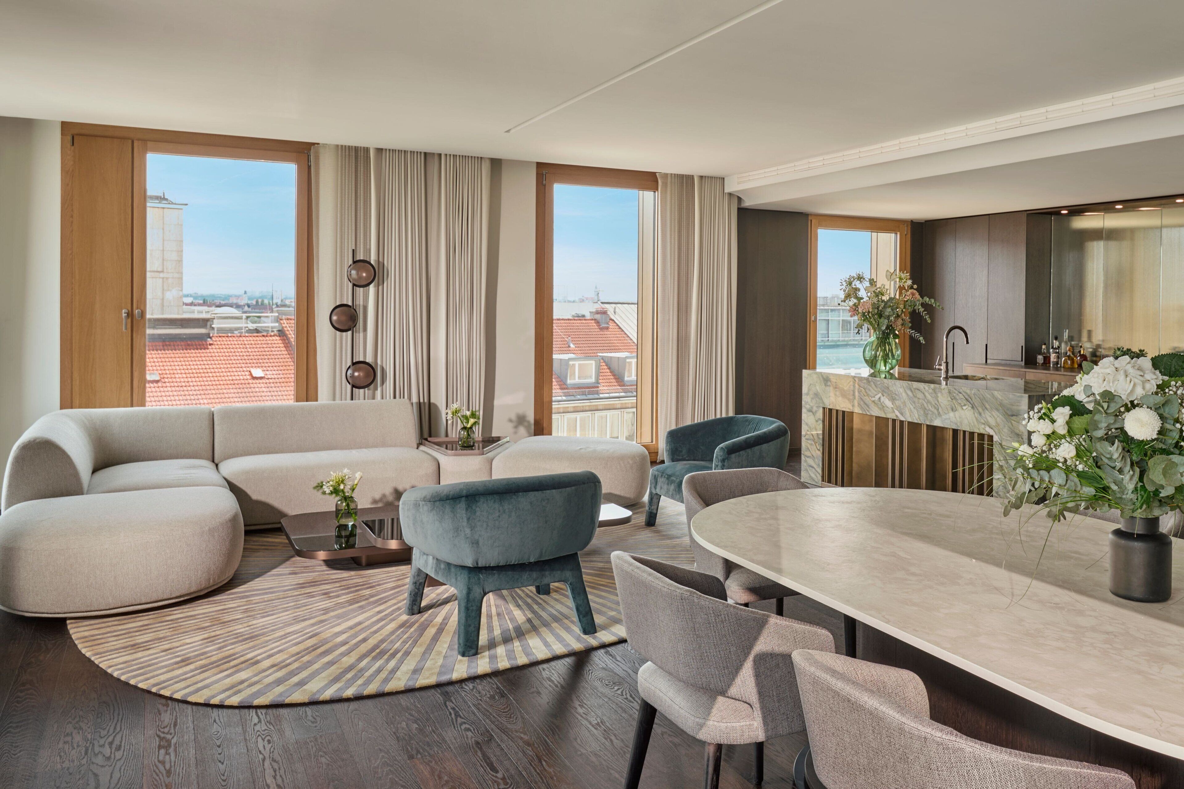 A modern living room with a sectional sofa, a round dining table, and a view of the cityscape through large windows.